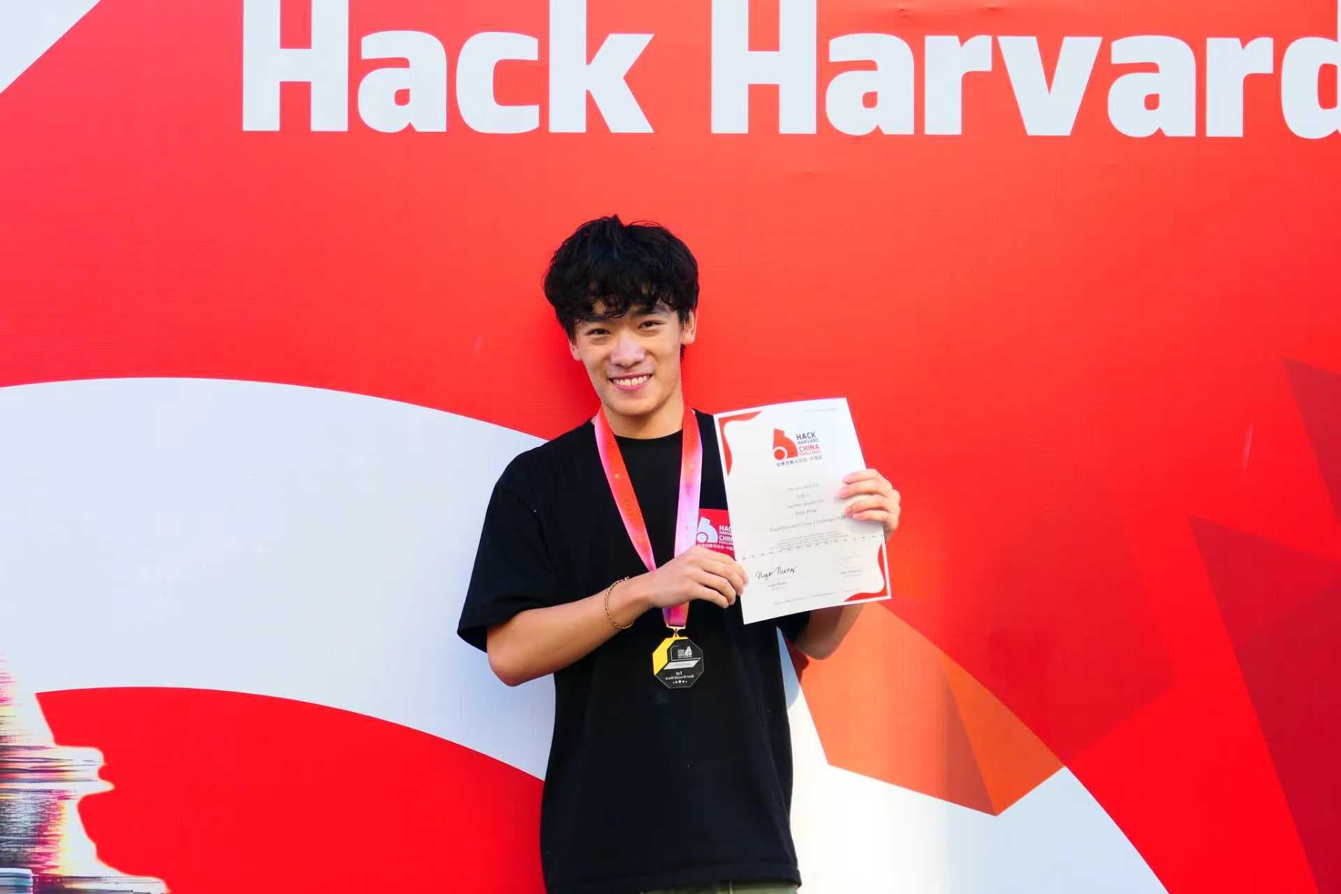 Alan holding a certificate in front of the HackHarvard backdrop