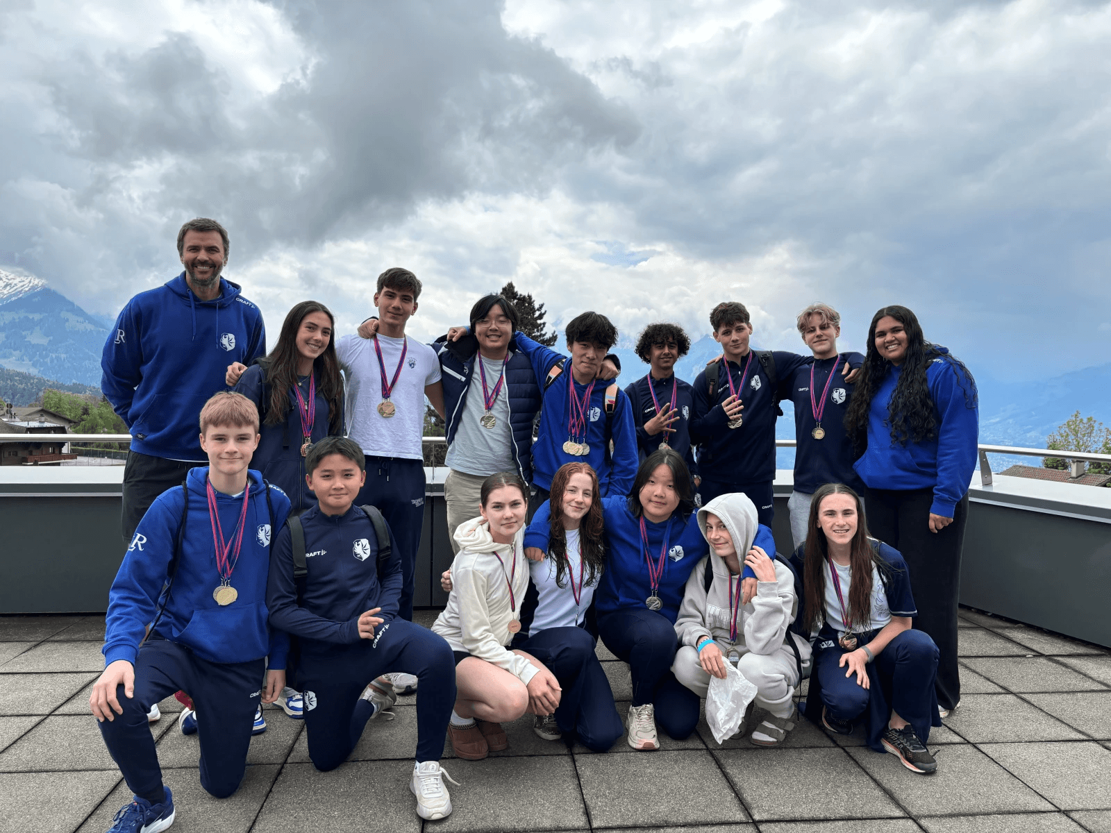 The swim team with their medals on a rooftop