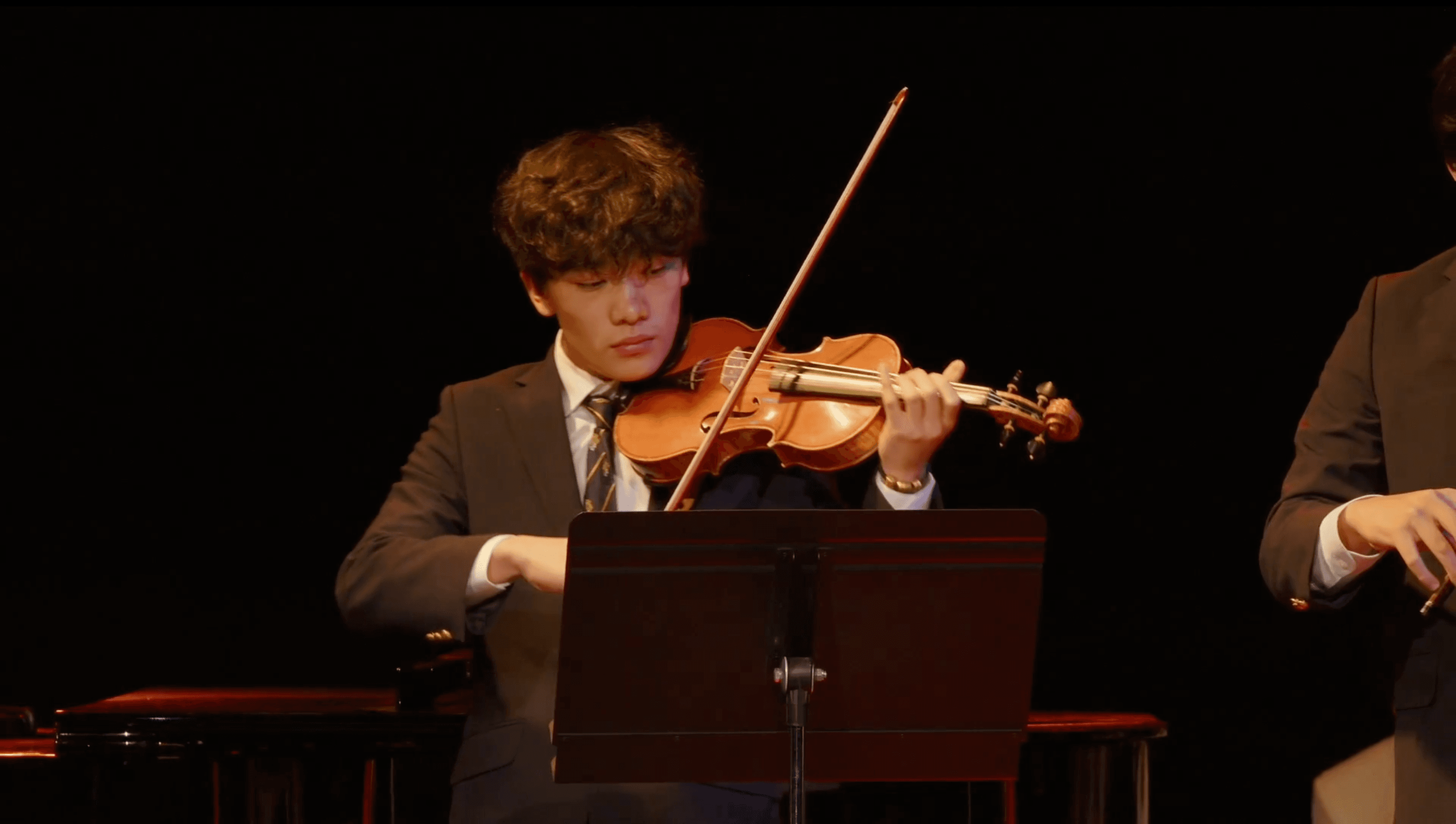 Alan performing violin in a dark hall