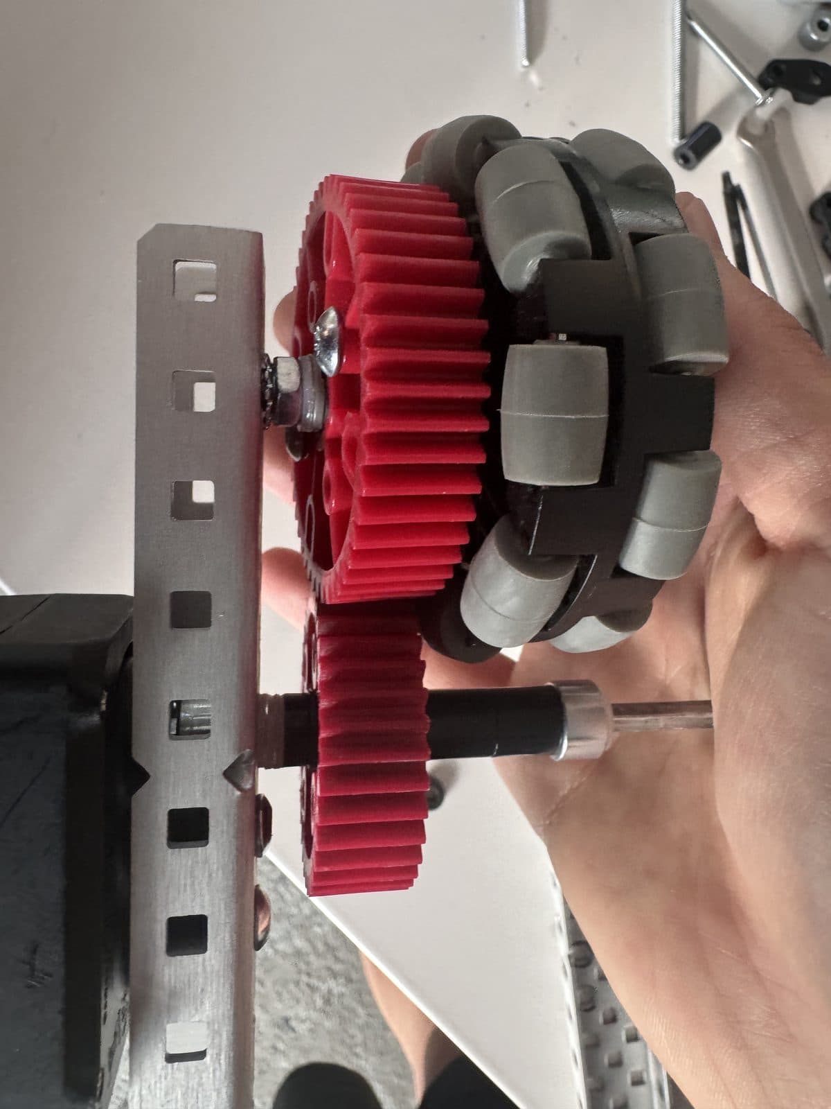 A red drive gear held up to the camera